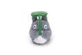 A plush toy shaped like a gray cartoon creature with a green leaf cap and a green vertical strap, photographed on a plain white background.
