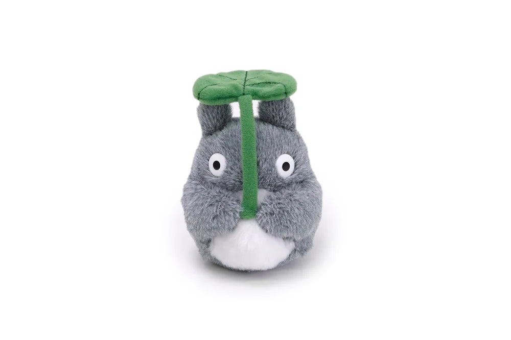 A plush toy shaped like a gray cartoon creature with a green leaf cap and a green vertical strap, photographed on a plain white background.