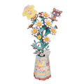 A colorful 3D papercraft model of a flower bouquet in a patterned vase, featuring cartoon-style characters on the petals, set against a plain white background.