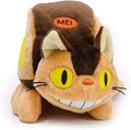 A plush toy shaped like a cat wearing a brown backpack, with yellow eyes, a smiling mouth showing white teeth, and an orange patch on the backpack that reads 'MEI'.