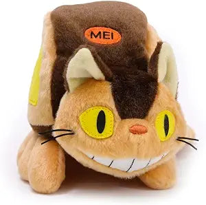 A plush toy shaped like a cat wearing a brown backpack, with yellow eyes, a smiling mouth showing white teeth, and an orange patch on the backpack that reads 'MEI'.