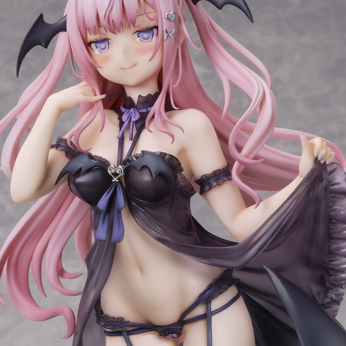Anime character figurine with pink hair and black and purple outfit on a gray background