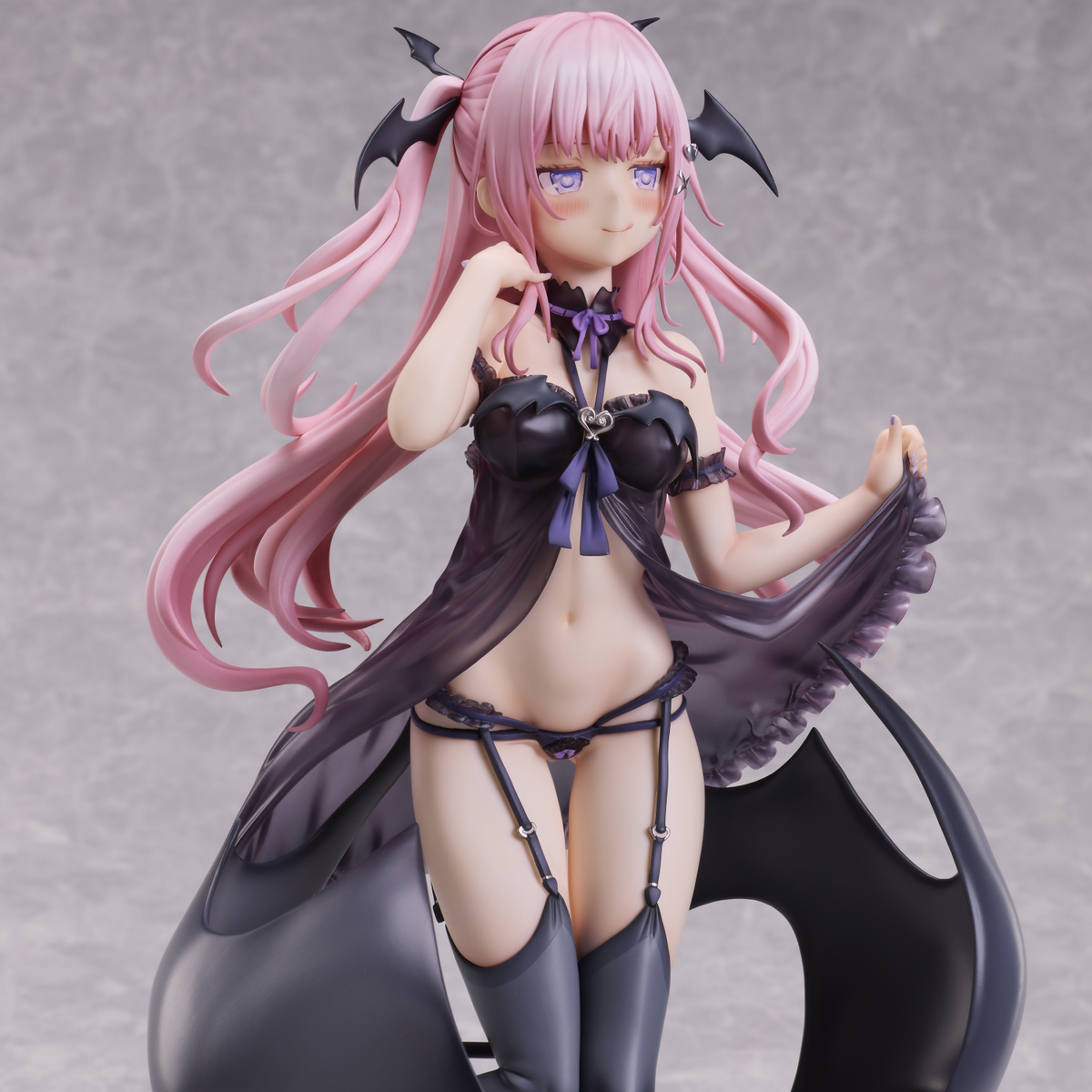 Anime character figurine with pink hair and black outfit on a gray background