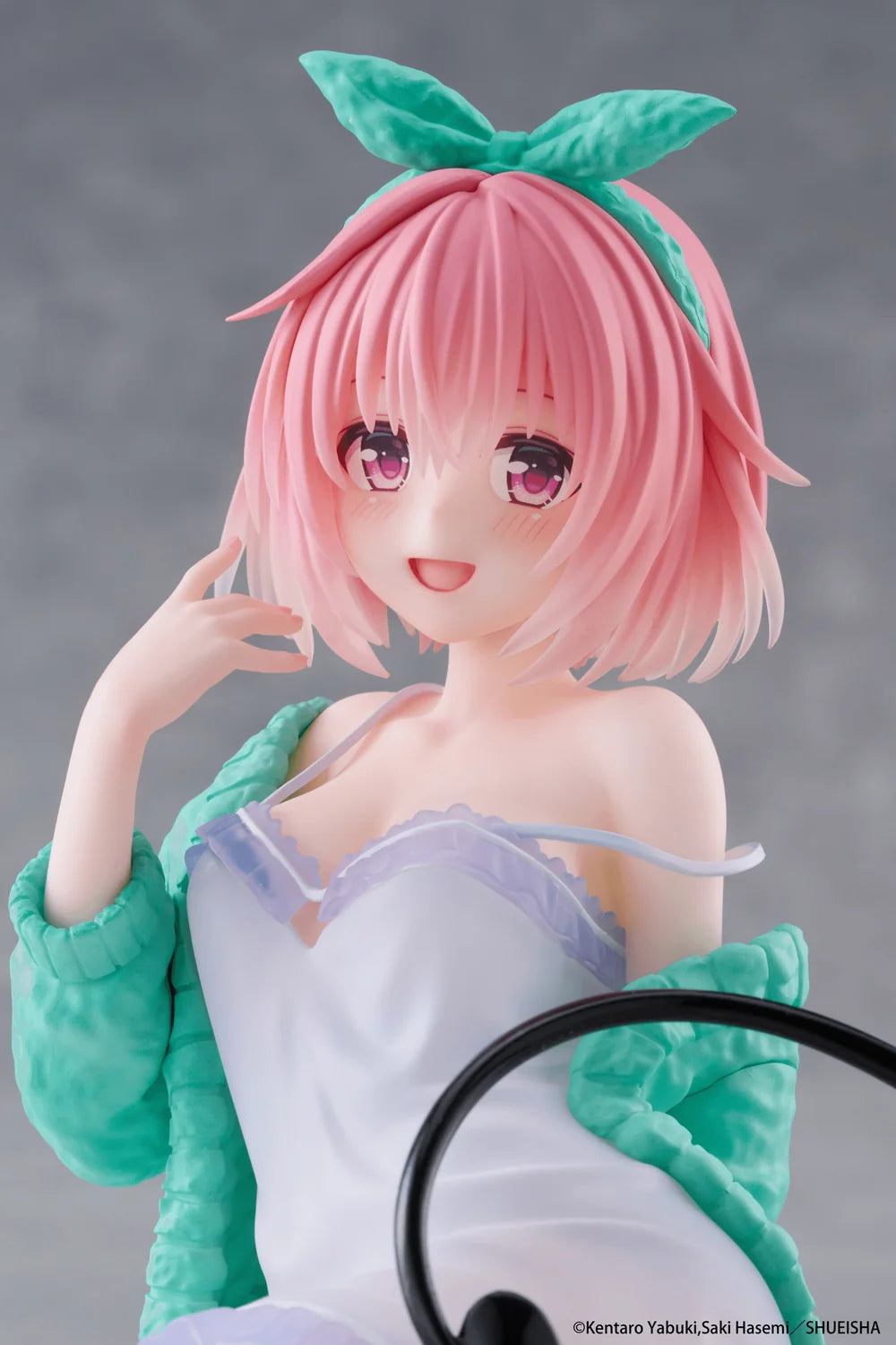 Anime character figurine with pink hair and green headband against a gray background