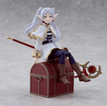 Figurine of a character with white hair and elf-like ears, sitting on a treasure chest.
