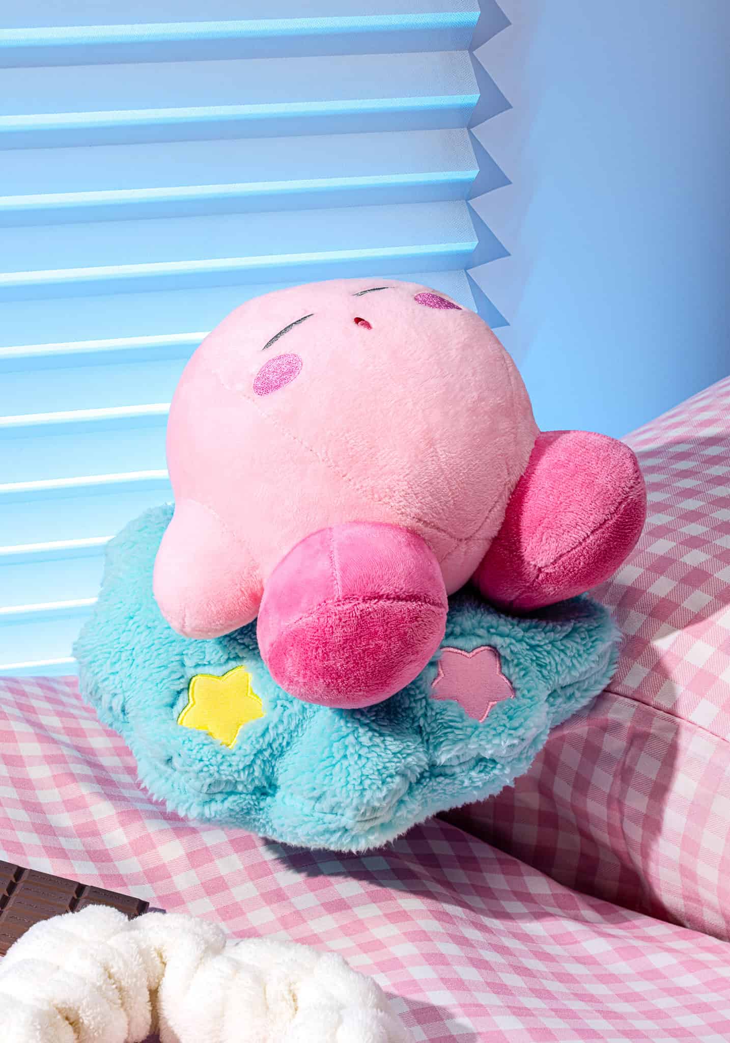 Plush toy with pink face and blue body on a checkered surface