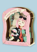 A 3D papercraft art piece depicting the anime character Aria Forger sitting inside a pink book frame, with 'Aria Forger' written on a banner at the top, set against a solid light blue background.