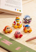 Four colorful character figurines on a tiled floor next to an open book.