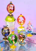 Collection of decorative figurines with colorful designs on a reflective surface.