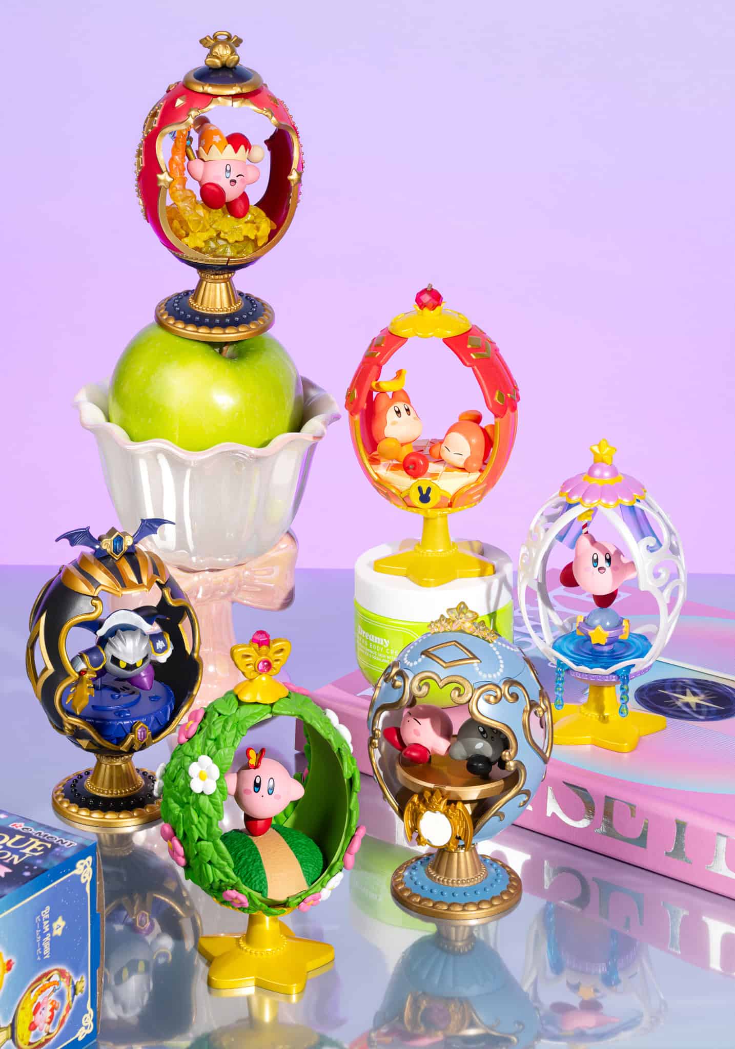 Collection of decorative figurines with colorful designs on a reflective surface.