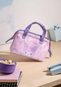 Pink handbag with cartoon character on a table with popcorn and stationery items
