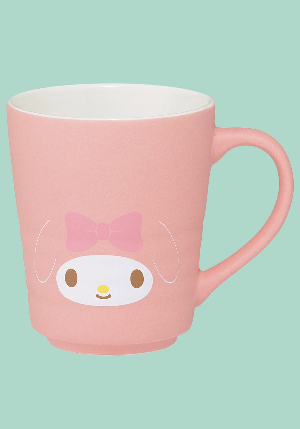A pink ceramic mug featuring a cartoon character face with a pink bow, on a solid mint green background.