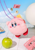 Pink plush toy with a face on a tiled floor with various items around