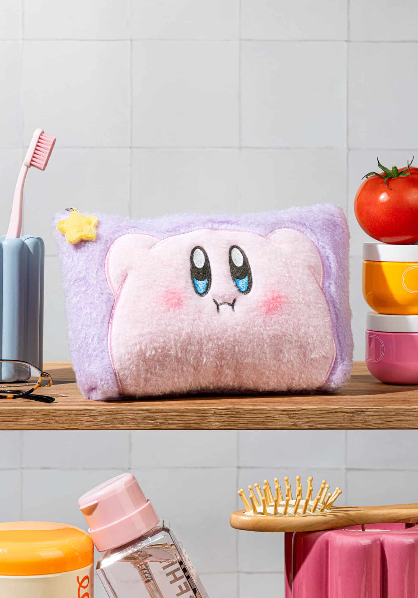 Plush toy resembling a character with a purple head and pink body on a shelf in a bathroom.