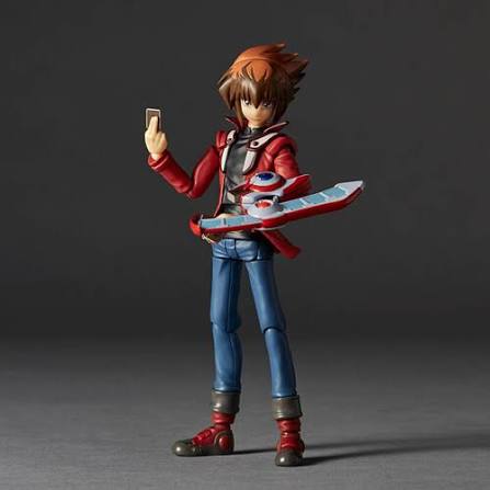 Action figure of a character in a red and blue outfit holding a device against a dark background