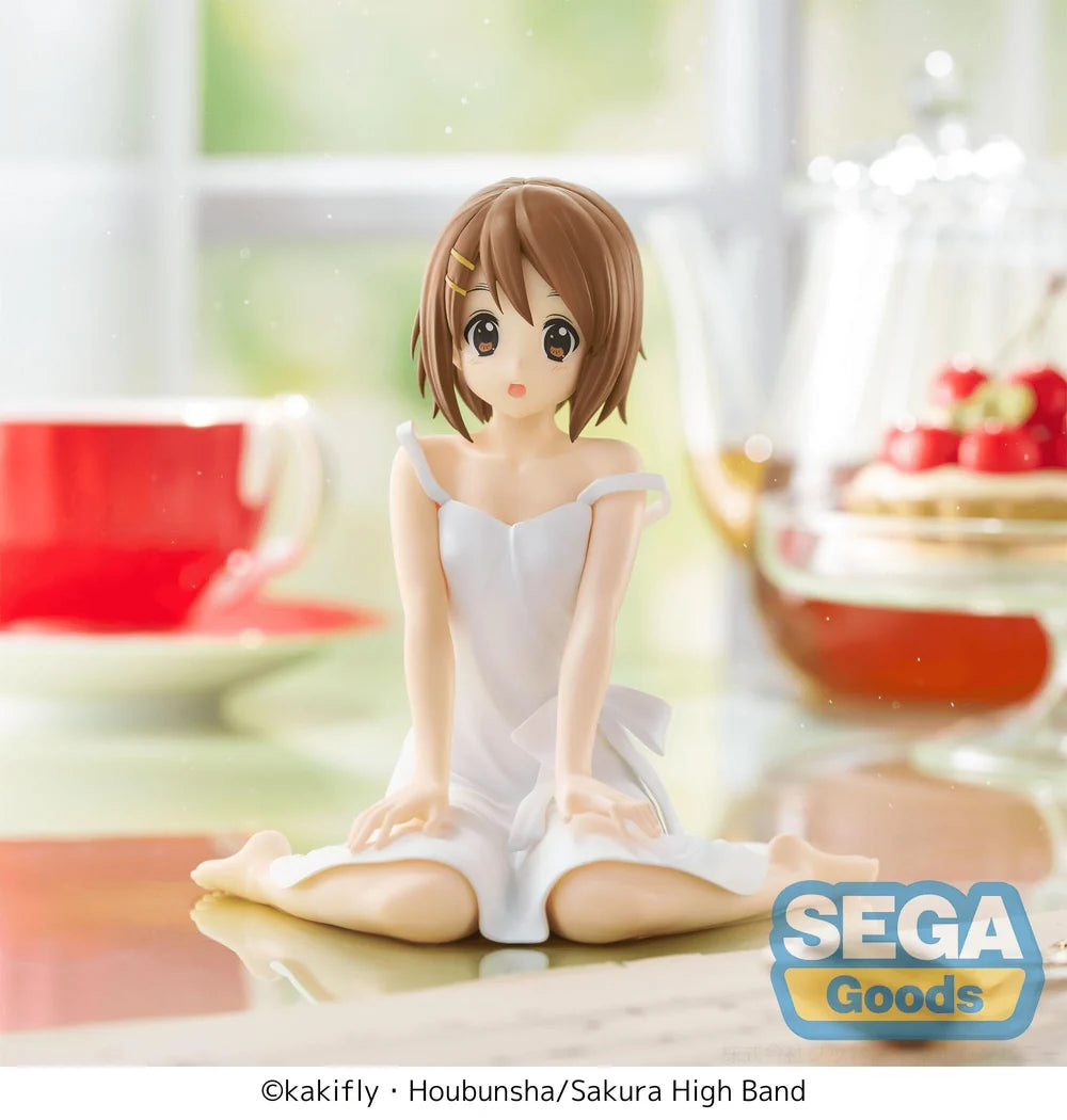 Anime figurine of a character in a white dress sitting on a table with blurred background