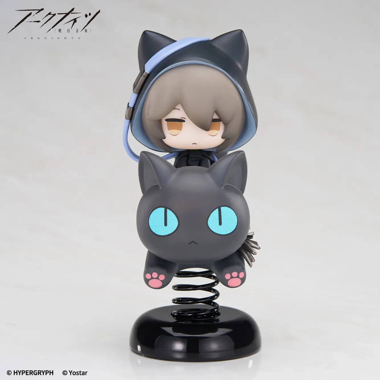 A collectible anime figure of a gray-haired character in a black cat hood with a spring-mounted black cat below, displayed on a glossy black base against a light gray studio background. The Hypergryph and Yostar logos are visible in the corners.