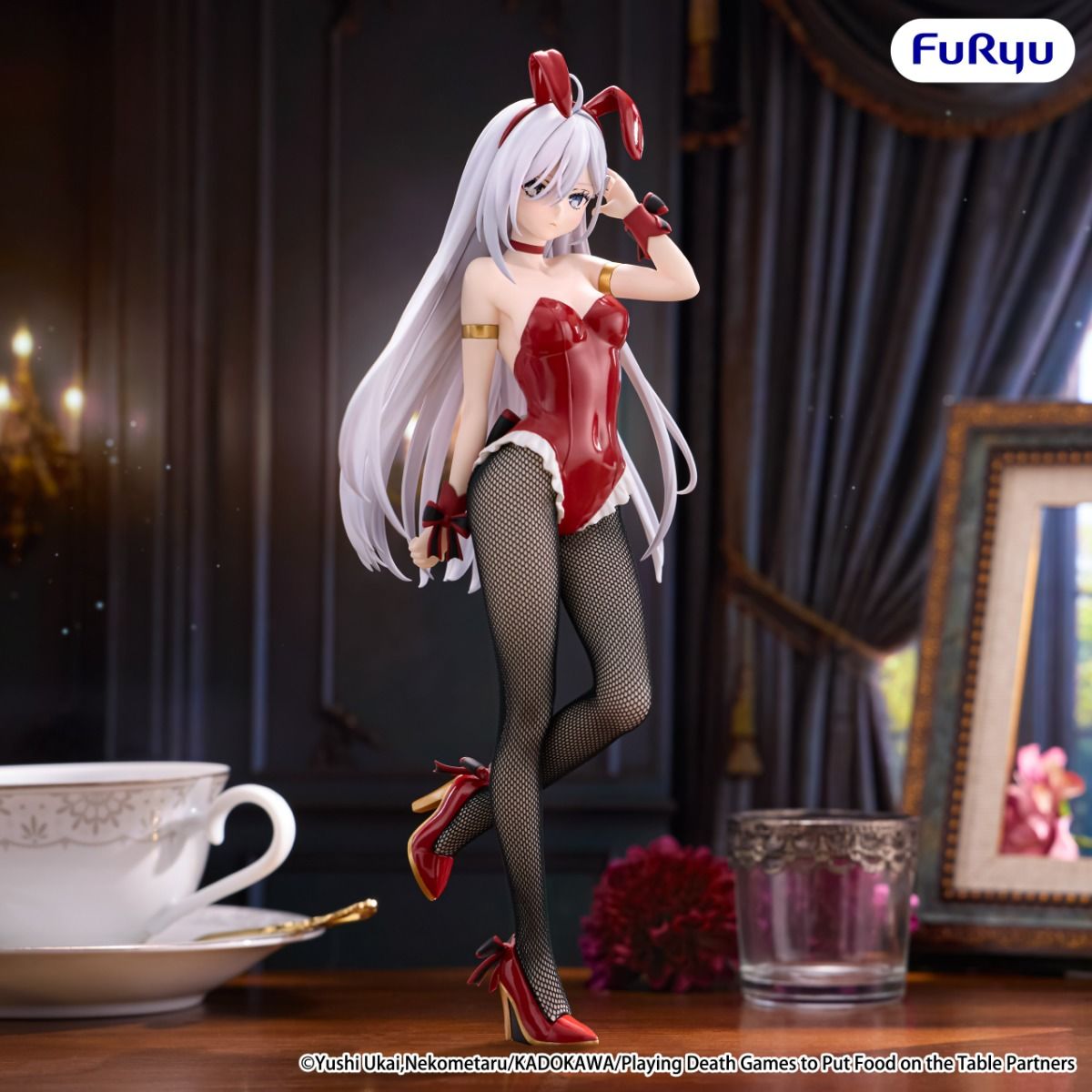 Anime character figurine in a red outfit with bunny ears on a table with a cup and saucer.