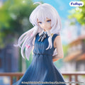 Figurine of a character in a blue dress with white hair, set against a blurred outdoor background.