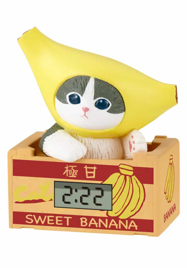 Toy figure of a cat in a banana costume with a digital clock inside a 'Sweet Banana' crate.