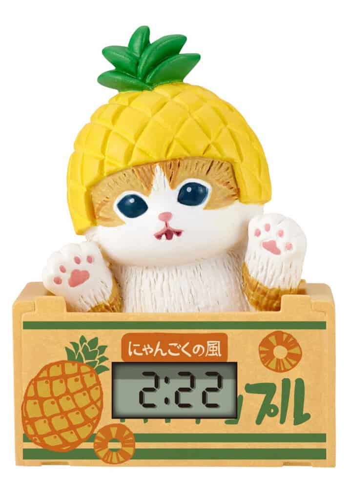 Cat figurine with pineapple hat on a digital clock display