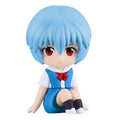 A chibi-style anime figurine of a girl with short light blue hair, red eyes, and a blue-and-white outfit with a red bow, seated against a plain white background.