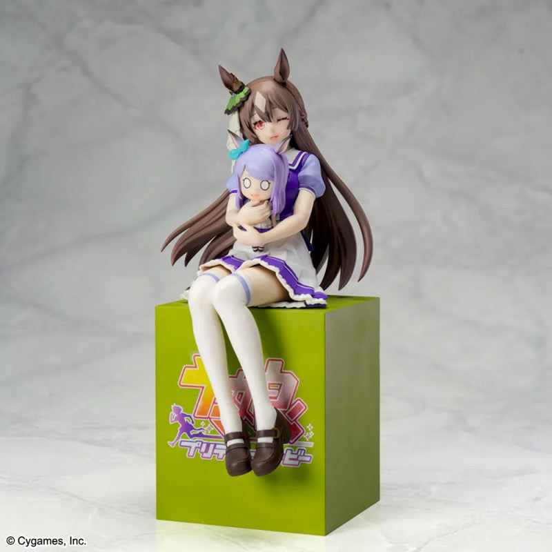 Anime figurine of a girl with brown hair and a purple-haired child on a green base with a logo.