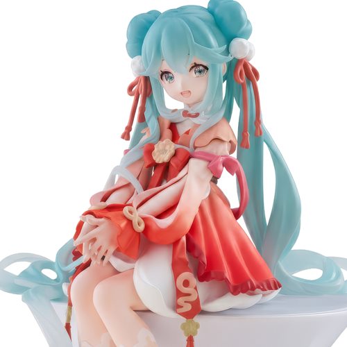 A collectible figurine of Hatsune Miku with turquoise hair and a red and white traditional-style dress, seated on a white platform against a plain white background.
