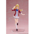 A collectible anime figurine of a blonde female character in a school uniform, posed mid-step on a clear round base against a pink studio background.