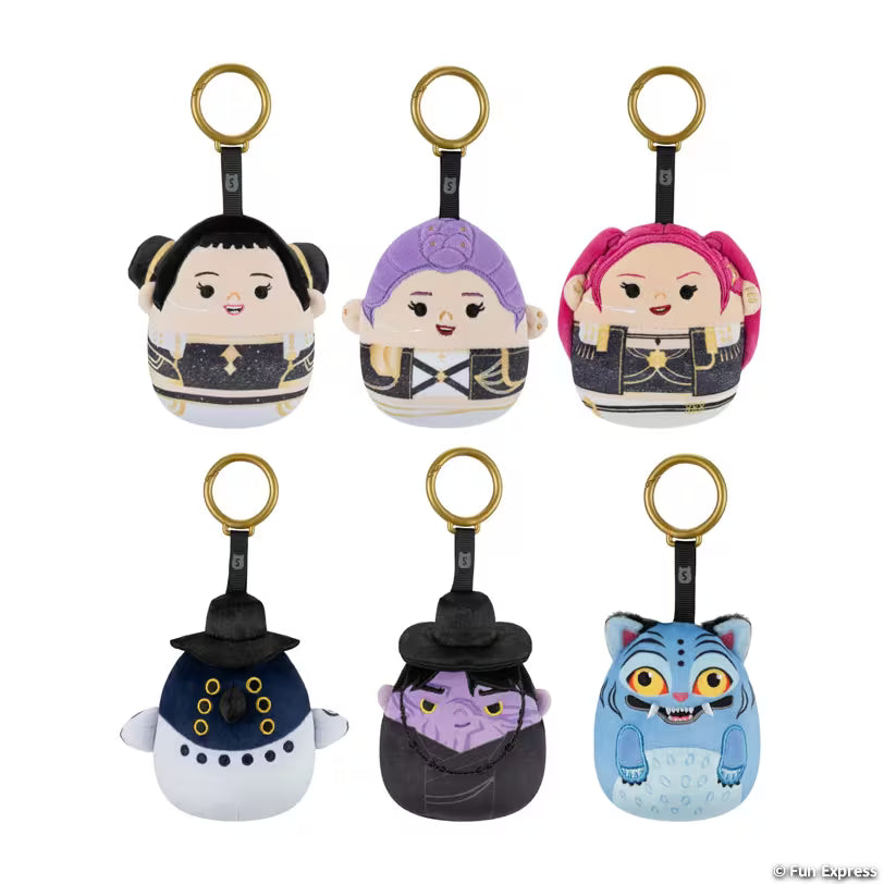 Six small plush character keychain bags arranged in two rows on a plain white background. Each bag has a gold key ring and a black strap, and the characters shown include a black-haired figure, a purple-haired figure, a pink-haired figure, a white figure with a dark blue hat, a purple-faced figure in a dark hat, and a blue tiger-like figure.