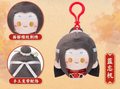 A plush character keychain or bag charm shown on a warm beige textured background, with two circular detail callouts on the left and Chinese text labels. The product is a small stuffed character with dark gray hair, a red top, and a red clip, with close-up insets highlighting embroidered facial details and hair accessories.