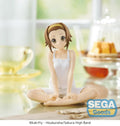 Figurine of a character in a white outfit sitting cross-legged on a table with a blurred background