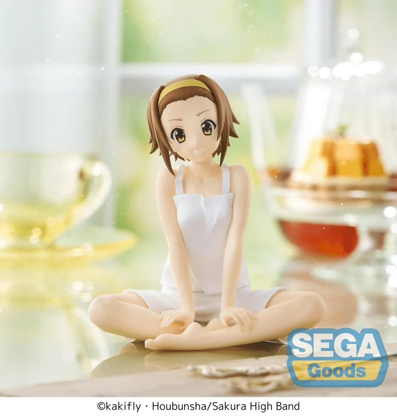 Figurine of a character in a white outfit sitting cross-legged on a table with a blurred background