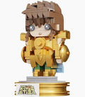 A block-style toy figurine of a character in gold armor with brown hair, standing on a display base against a plain white background.