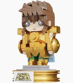 A block-style toy figurine of a character in gold armor with brown hair, standing on a display base against a plain white background.