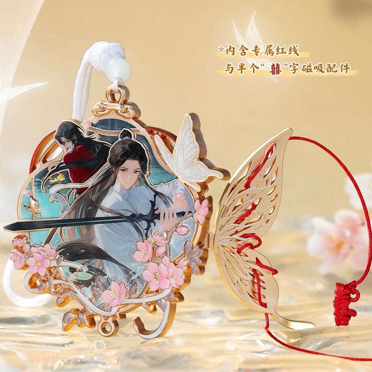 A decorative metal charm or pendant with an illustrated female figure, pink blossoms, a butterfly, and red cord, shown on a soft beige background with Chinese text in the upper right.